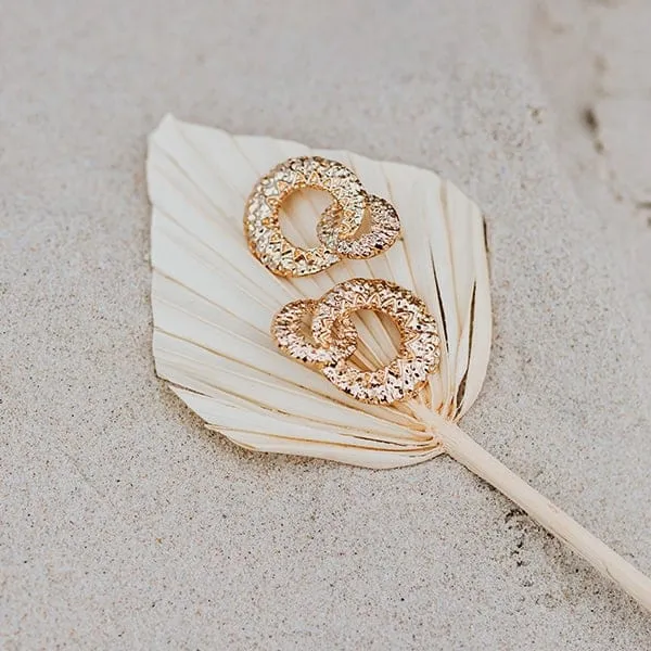Gold earrings displayed on a dried leaf